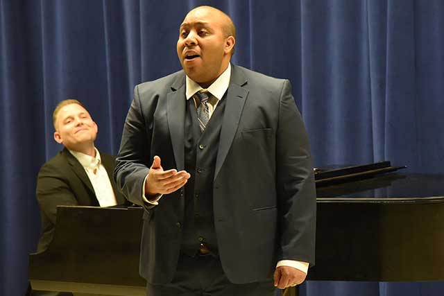 Man singing in front of a piano