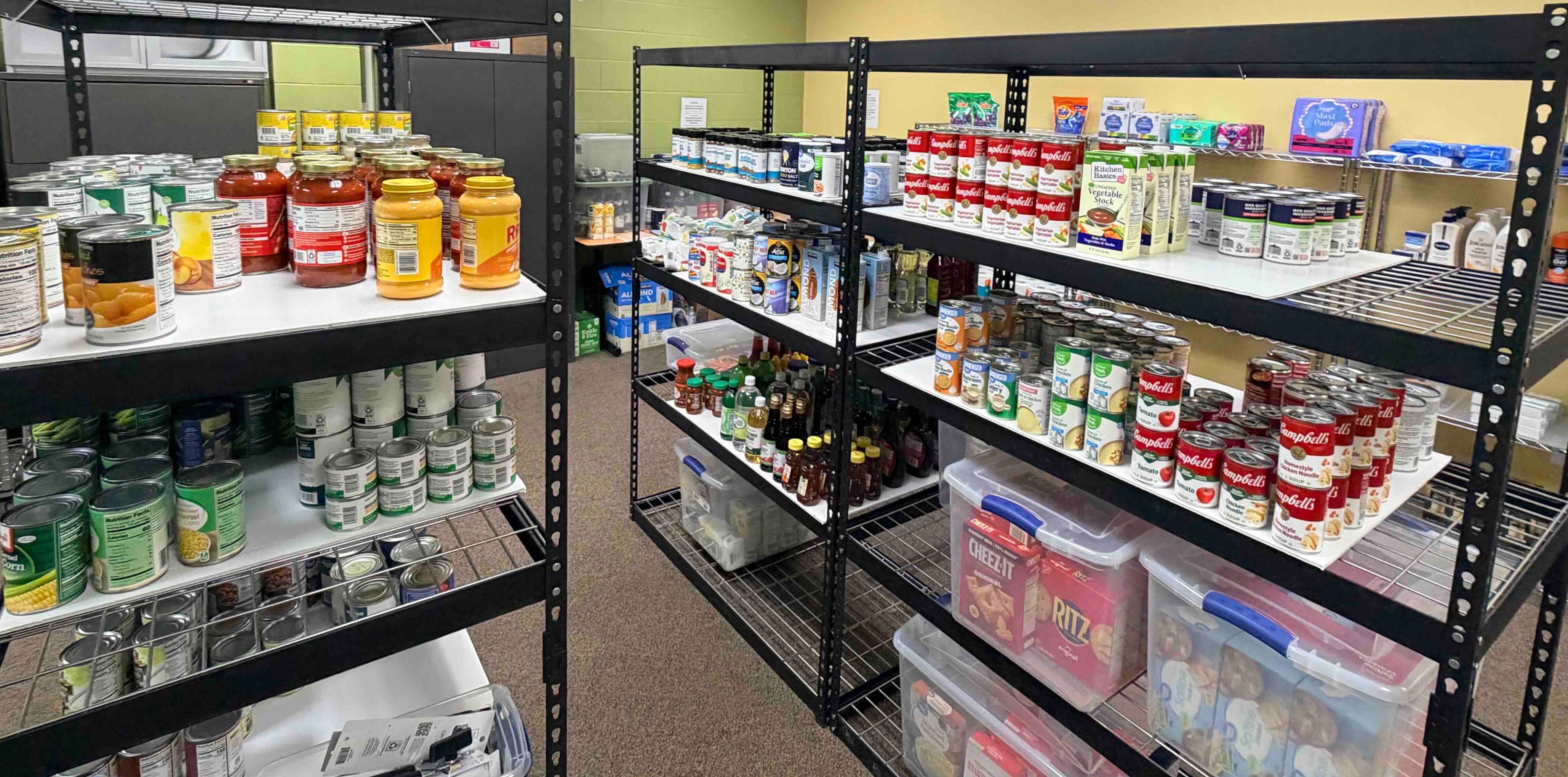 A room with black metal shelves storing organized items of nonperishable foods.