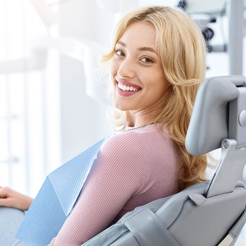 A woman in a dental chair looking over her shoulder and smiling A woman in a dental chair looking over her shoulder and smiling