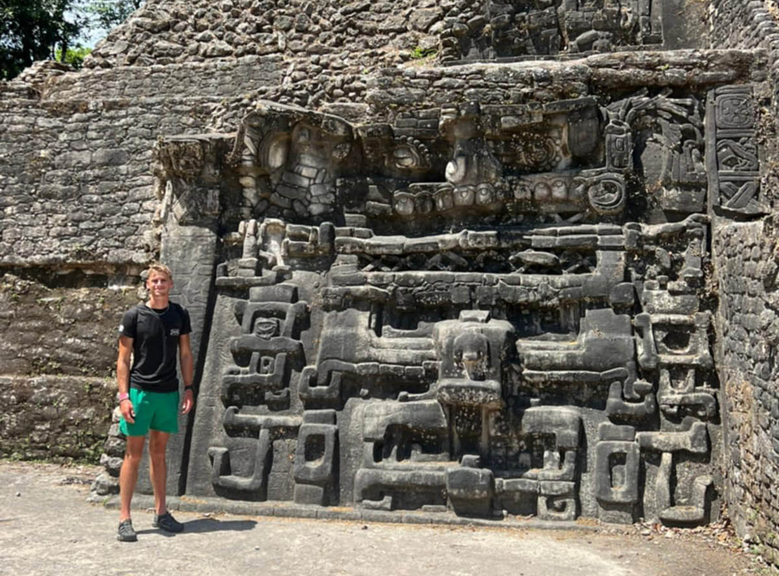 A DMACC student stands at a Mayan wall during a study abroad semester