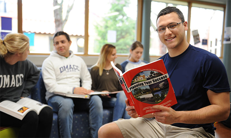 DMACC students, one is reading a book.