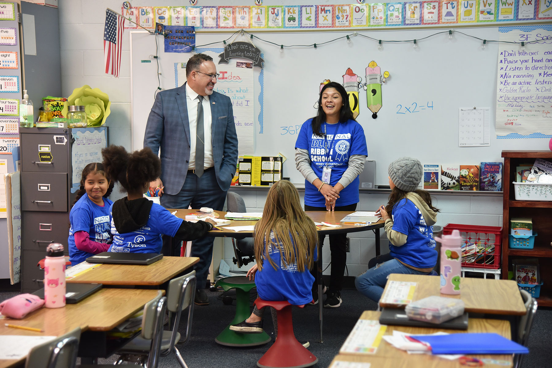 U.S. Secretary of Education Dr. Miguel Cardona​​ smiles as he listens to third-grade teacher Daisy Diaz work with her students at Perry Elementary School on Dec. 7, 2023. When Cardona asked students what they liked best about their school, he said the most frequent answers were their teachers, pizza and ice cream —​ in that order!